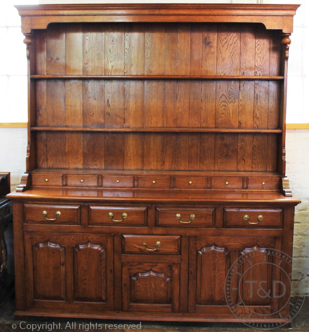 A George III style golden oak dresser, three open shelves and seven small drawers,