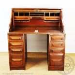 An early 20th century oak roll top desk, with tambour enclosing a fitted interior,