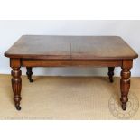 An Edwardian oak extending dining table, with canted corners, on turned and fluted legs,