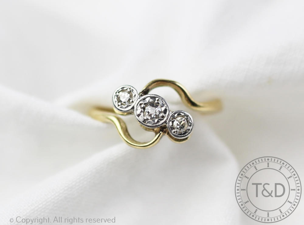 A three stone diamond ring in cross-over setting, the three graduated,