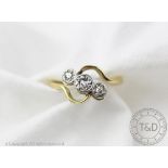 A three stone diamond ring in cross-over setting, the three graduated,