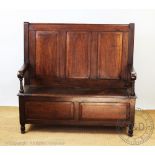 An 18th century style oak settle, with three panelled back above a box seat with hinged lid,