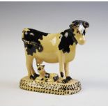A Staffordshire pottery creamware Friesian cow in the style of Thomas Whieldon,