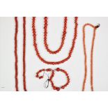 An assorted collection of coral coloured bead necklaces,