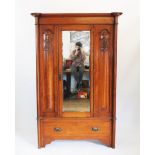 An Art Nouveau oak bedroom suite comprising; a single door wardrobe and a mirror back dressing chest