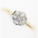 A diamond floral cluster ring, the seven old cut diamond claw set to white metal to a tapering