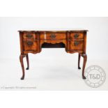 A reproduction George II style walnut serpentine desk, with an arrangement of five drawers, on