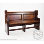 A Victorian pitch pine pew, having a twin panel back and rear book shelf above a board seat,