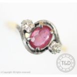 A pink sapphire and diamond three stone cross-over ring, the central sapphire within four claw