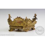 A cast gilt metal planter, of oval form, with foliate designs and seated putti detail, raised upon