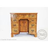 A George III style walnut knee hole desk, with an arrangement of seven drawers around a central