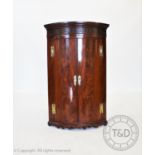 A George III flame mahogany bow front hanging corner cupboard , with a moulded cornice above a blind