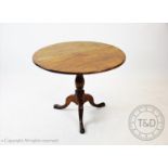 A George III tilt-top mahogany tripod table, the circular top supported on a baluster shaft and