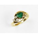 An emerald and diamond 18ct gold ring, the central heart-shaped emerald flanked by three brilliant