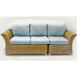 A wicker conservatory three seater sofa, with loose back and seat cushions covered in duck egg