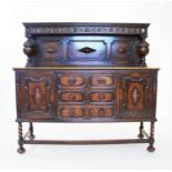 A 1930's oak Jacobean revival sideboard, the raised back flanked by carved bulbous uprights, above