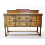 An early 20th century golden oak Jacobean revival sideboard, with a dwarf back above a rectangular