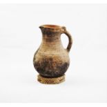 An early stoneware jug of inverted baluster form, with shaped handle and inscribed decoration to the