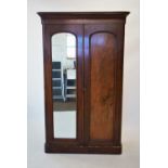 A Victorian mahogany double wardrobe, with a cavetto cornice above a mirrored door and a panelled
