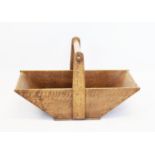 A late 19th century oak trug, of tapering form with a turned fixed overhead handle, 60cm long