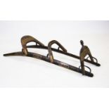 A hardwood and brass mounted camel saddle, the two curved parallel rails braced by three arched back