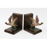 A pair of oak bookends, early 20th century, each mounted with a cold painted bronze model of a