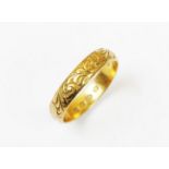 An 18ct gold wedding band, with engraved scrolling foliate detail, ring size T, weight 4.6gms