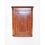 A George III oak flat front hanging corner cupboard, with a dentil cornice above a single door