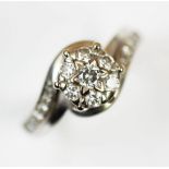 A seven stone diamond cluster ring, the seven brilliant cut diamonds claw set in a white metal
