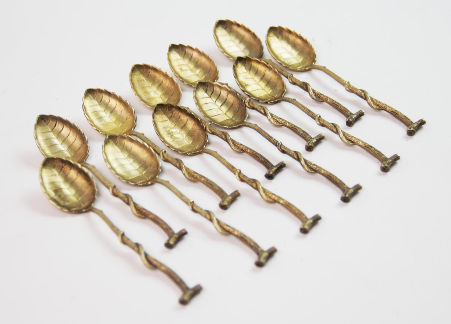 A set of eleven continental silver gilt teaspoons, the bowls designed as leaves, the handles of twig