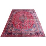 A large red ground Persian Mashad carpet with traditional medallion design and unique colours, 390cm