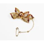 A ruby and diamond set 18ct gold brooch, the pierced design bow shaped brooch channel set with