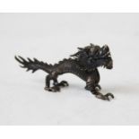 A Chinese white metal model of a dragon, with three clawed feet, scaled body and spiked tail, 9cm