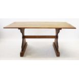 A mid 20th century oak refectory table, raised upon two trestle type supports, each applied with