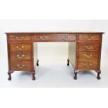 A George II style mahogany desk, 20th century, having a gilt tooled leather writing surface within a