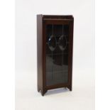 An Arts and Crafts glazed oak bookcase,with a galleried top above a leaded and stained glass door,