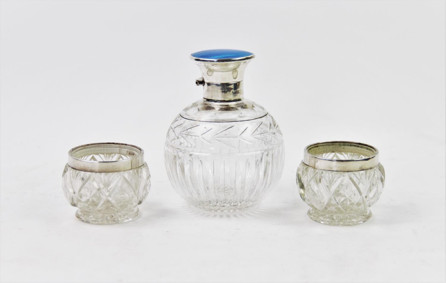 An early 20th century silver topped scent bottle, the hinged cover with blue guilloche enamel top,