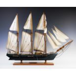 A wooden model of a three masted schooner in full sail, with painted hull, brass details and