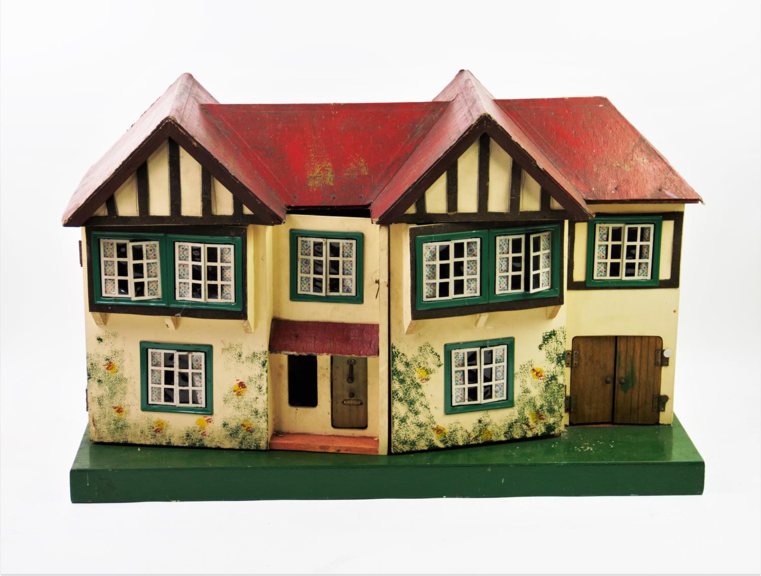 A 1930's black and white dolls house, with a red roof and hinged front, concealing four rooms and
