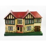 A 1930's black and white dolls house, with a red roof and hinged front, concealing four rooms and