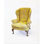 A George II style wing back armchair, with padded out-swept wing backs and arms enclosing the shaped