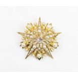 A 20th century diamond and pearl set starburst cluster brooch/pendant, the central old cut diamond