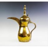 A middle eastern brass Dallah coffee pot of large proportions, of traditional form with solid