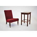 A Victorian red velour low seat nursing chair, raised upon bobbin turned front legs and castors,