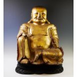 A large and impressive giltwood and gesso model of laughing Buddha, depicted seated holding a