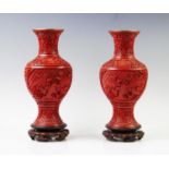 A pair of Chinese cinnabar lacquer vases, 20th century, each of baluster form and raised on hardwood