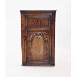 An 18th century style oak hanging corner cupboard, 20th century, the single door with a nulled