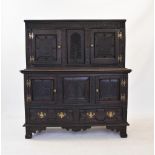 A 17th century style carved oak court cupboard, the upper section with a pair of doors flanking a