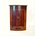 A 19th century mahogany bow front hanging corner cupboard, with a moulded cornice above a pair of