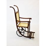 A 1920's stained beech wood and rattan wheel chair, the curved down swept supports braced by the